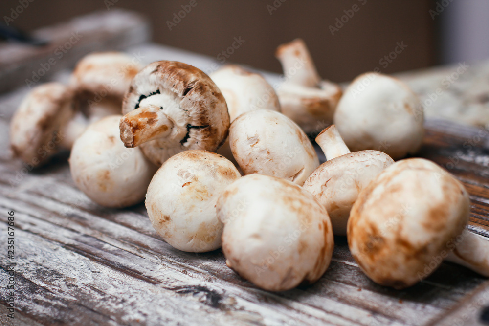 Champignon mushrooms. Small white brown mushrooms on wooden table. 