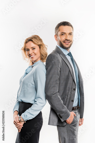 side view of professional  businessman and businesswoman standing together and smiling at camera isolated on white