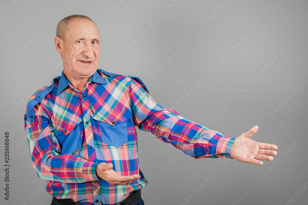 The elderly person point away. Serious Mature man pointing finger to the side, on grey background, copy space The elderly person point away. Serious Mature man pointing finger to the side, on grey background, copy space