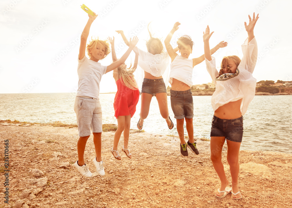 Obraz premium Cute teens jumping together on the beach in summer