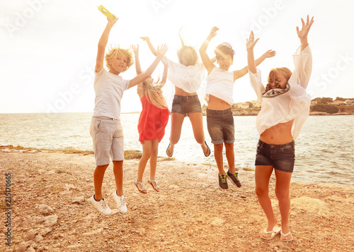 Cute teens jumping together on the beach in summer