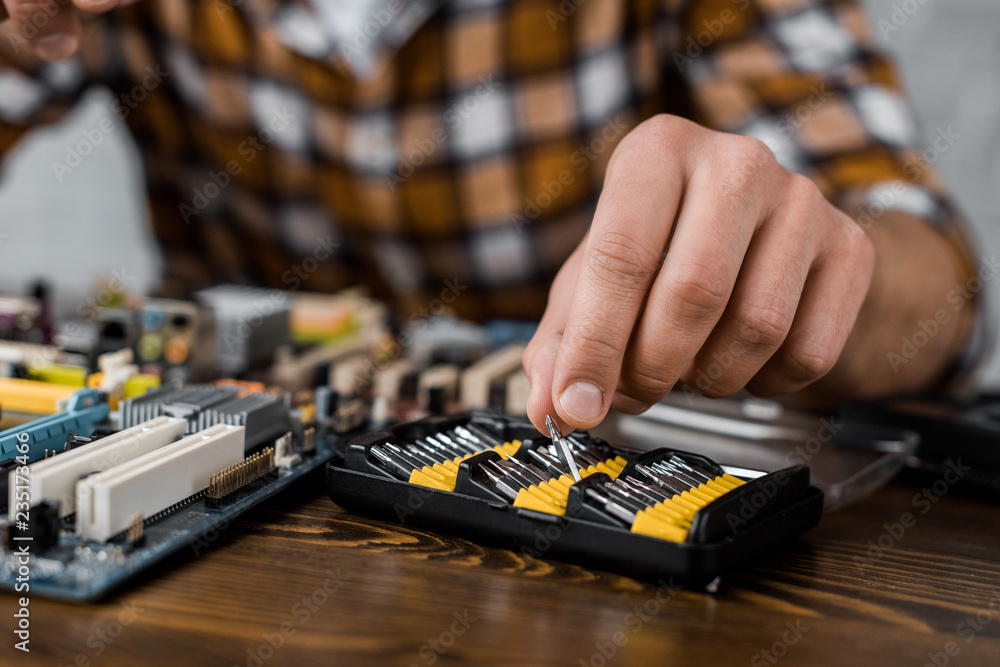 computer engineer taking screwdriver caps to repair motherboard computer engineer taking screwdriver caps to repair motherboard
