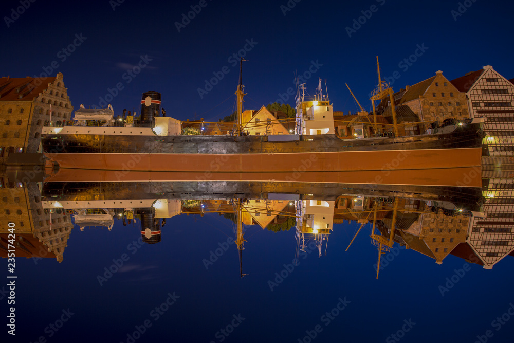 Reflections of the ship Soldek at night in the river Motlawa in the old city