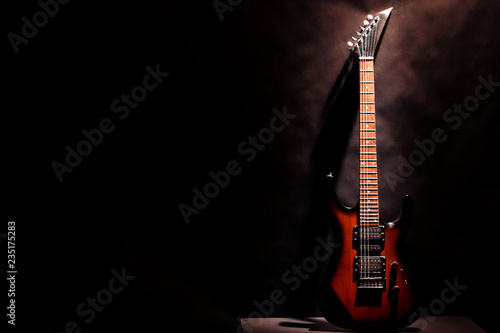 Red electric guitar on a dark background.