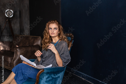 Artist painting on easel in studio. Female painter seen from side.