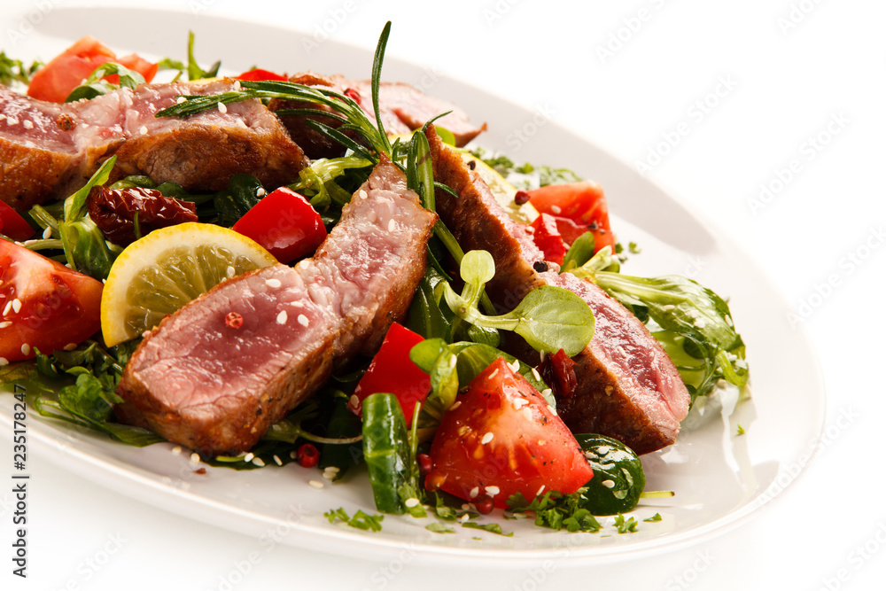 Fillet mignon - grilled beefsteaks with vegetables on white background Fillet mignon - grilled beefsteaks with vegetables on white background