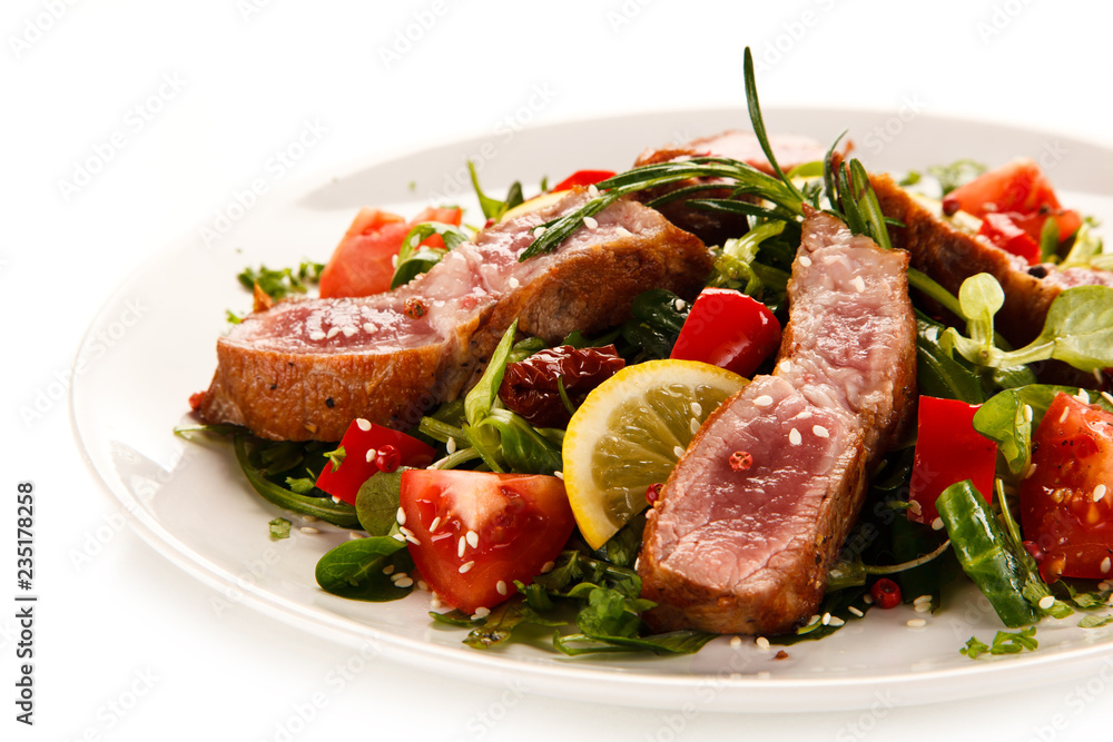 Fillet mignon - grilled beefsteaks with vegetables on white background Fillet mignon - grilled beefsteaks with vegetables on white background
