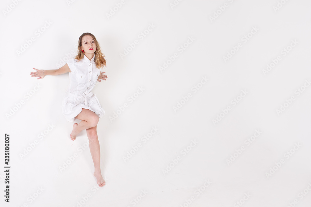 Pretty girl in white dress barefoot posing and dancing  in studio on white bachground 20 years old