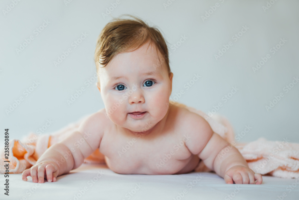 Cute baby covered with a bath towel lying on tummy Cute baby covered with a bath towel lying on tummy