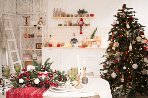 Interior light kitchen and red christmas decor. Preparing holiday dinner at home on the kitchen concept. Decorated new Year fir. Selective focus