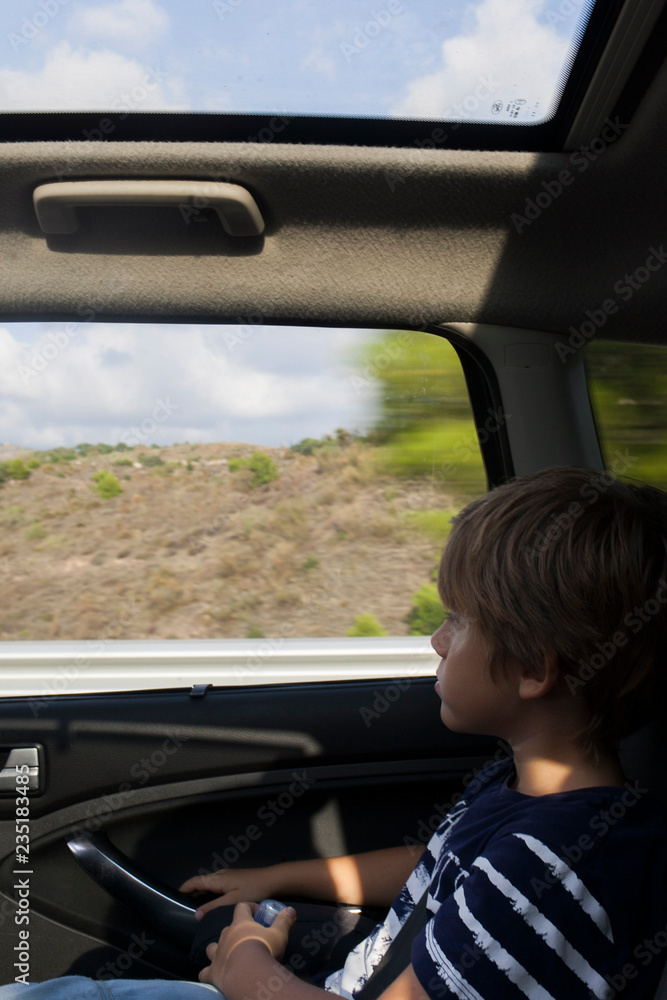 niño viajando dentro de un coche mirando paisaje por la ventanilla niño viajando dentro de un coche mirando paisaje por la ventanilla