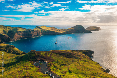 Aerial tropical island view in the middle of the ocean with rocky cliffs and green fields