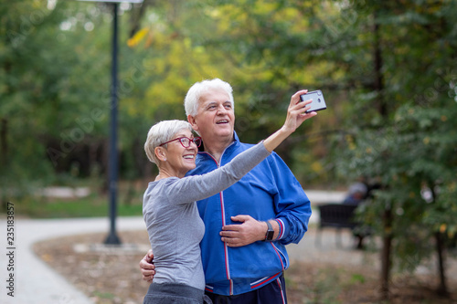 Mature couple taking selfie by mobile phone after jogging at the park