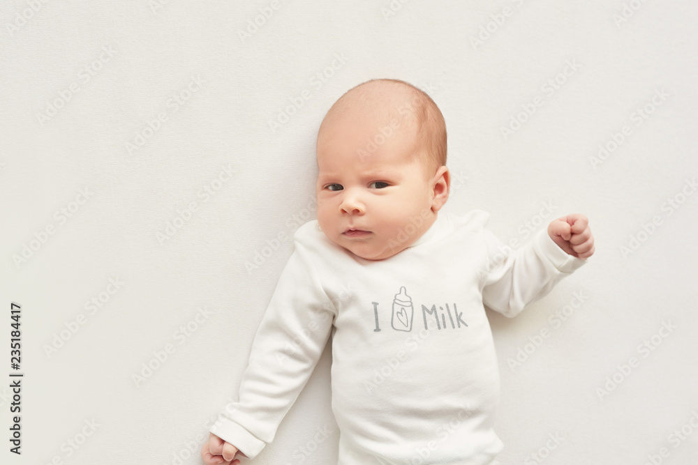 Cute newborn baby girl lies swaddled in a white blanket. Baby goods packaging template. Closeup portrait of newborn baby with smile on face. Healthy and medical concept. Cute newborn baby girl lies swaddled in a white blanket. Baby goods packaging template. Closeup portrait of newborn baby with smile on face. Healthy and medical concept.