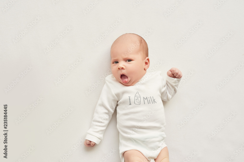 Cute newborn baby girl lies swaddled in a white blanket. Baby goods packaging template. Closeup portrait of newborn baby with smile on face. Healthy and medical concept. 