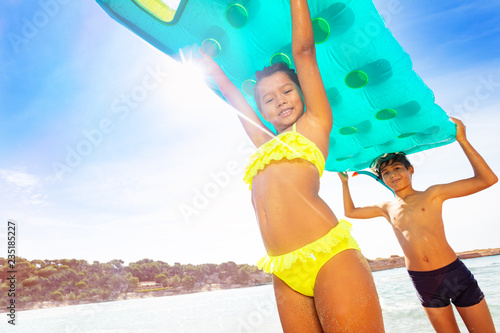 Happy boy and girl with swimming mattress overhead