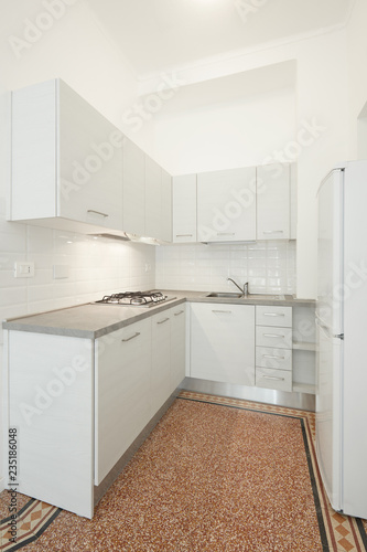 New, white wooden kitchen with gray stone top in renovated apartment interior