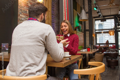 Man giving a present to his girlfriend in cafe and she is surprise