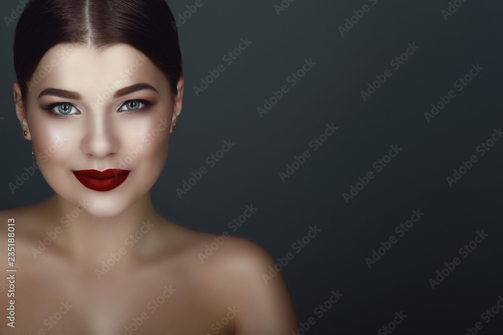 Fototapeta premium Close up portrait of beautiful smiling dark-haired model with perfect make up and centre part sleek bun. Isolated on grey background. Text space