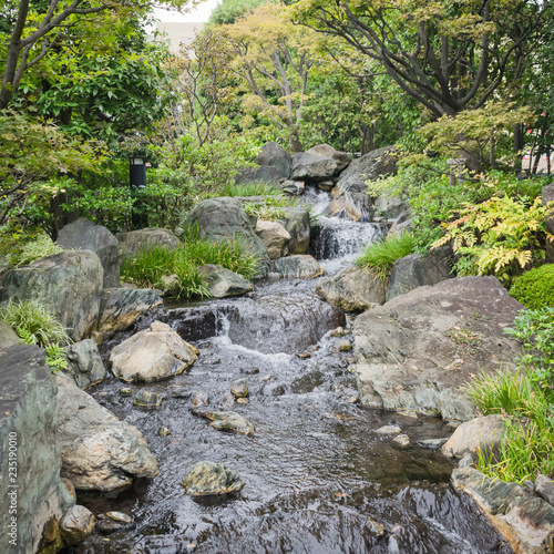 Nature background with view of traditional Japanese garden in Kanazawa, Japan, with rocks and artificial waterfall in November.