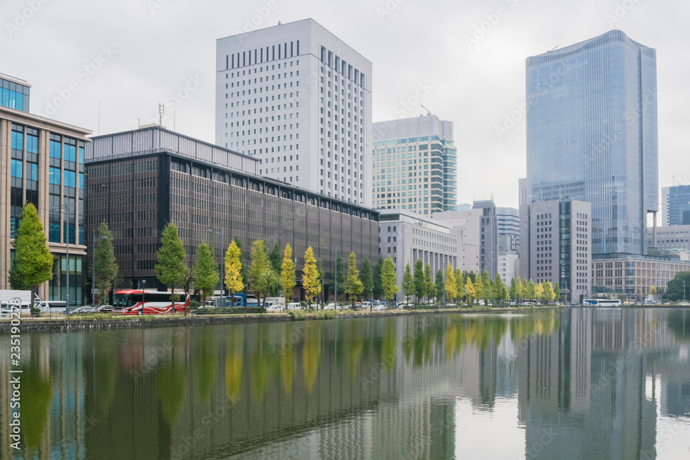 Urban background with Tokyo downtown Marunouchi district and water reflections of trees and buildings in November. Urban background with Tokyo downtown Marunouchi district and water reflections of trees and buildings in November.