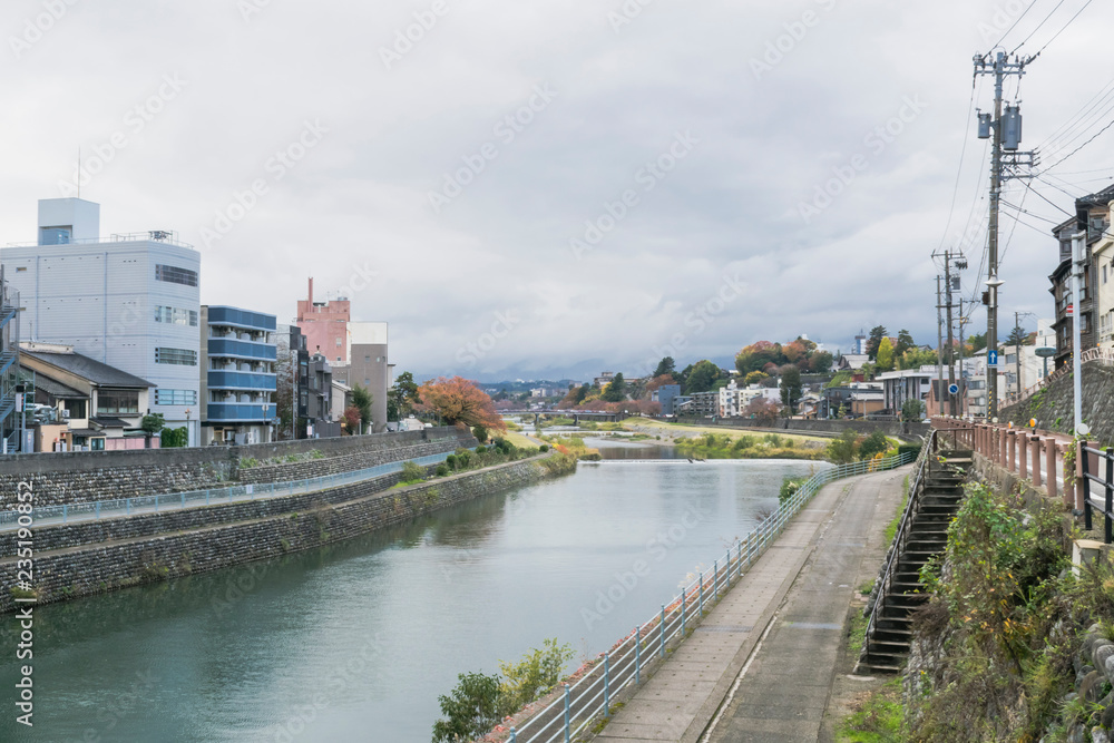 Urban or park background featuring Saigawa river and bridges across in residential district of Kanazawa, Japan, in cloudy autumn day in November. 