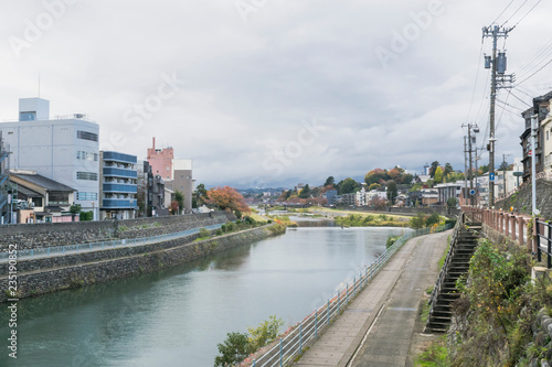Urban or park background featuring Saigawa river and bridges across in residential district of Kanazawa, Japan, in cloudy autumn day in November.  © abyrvalg_00