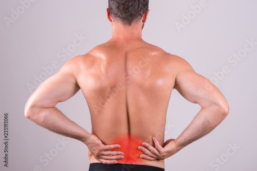 Back view of a shirtless man with lower back pain