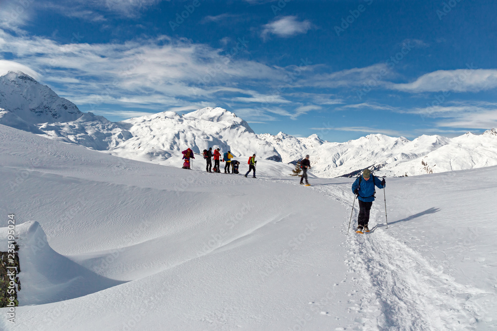 Some snowshoe hikers walk through the snow-covered Alps in winter in the canton of Graubünden in Switzerland.