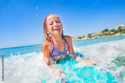 Happy teenage girl riding the wave on body board