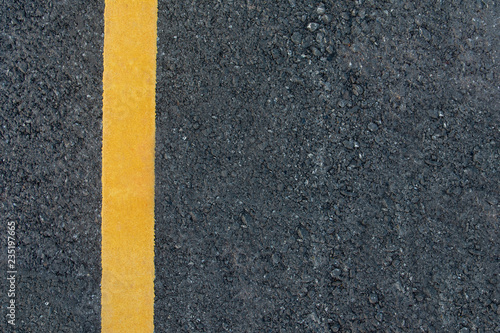 Yellow line on black asphalt road background with copy space © Achira22