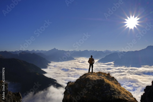 Person auf Berggipfel mit Panorama und Talnebel