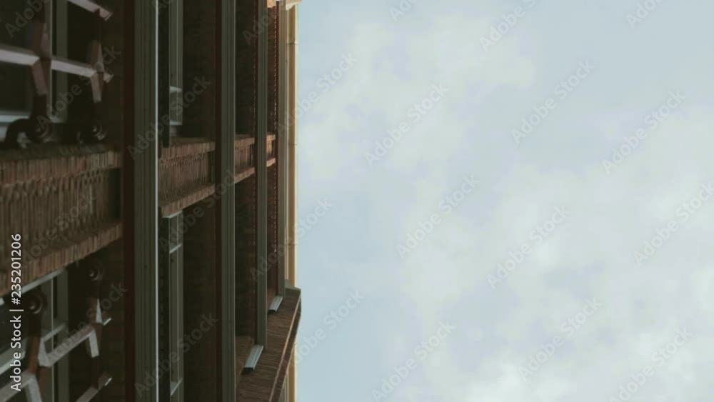 Thin clouds move over a blue sky above a brick facade building in a city. Thin clouds move over a blue sky above a brick facade building in a city.