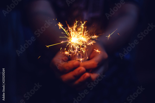 Woman hand holding a burning sparkler. Christmas and new year sparkler holiday background photo