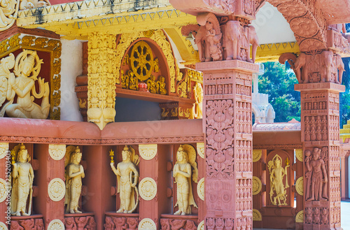 Details of the porch at the stupa of Sitagu International Buddhist Academy with statues of Nats (Spirits), wheel of dharma above the entrance and the ornate terracotta torana gate, Sagaing, Myanmar. photo