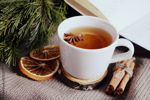 Cup of lemon tea, cinnamon, fir branch. Winter holidays concept. Cozy home