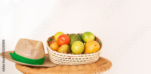 Basket of fruit and straw hat on the table. Agriculture concept image.