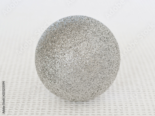 One shiny silver christmas ball with sparkles on a white textural background close up