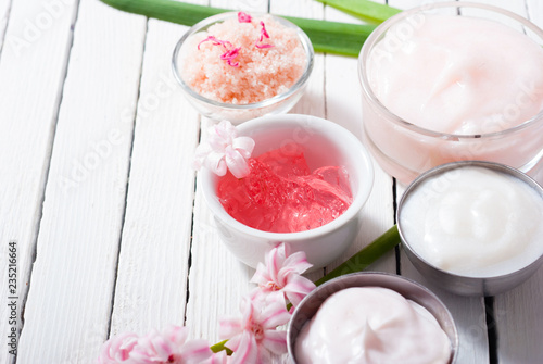 beauty and cosmetic creams with pink flowers on white wood