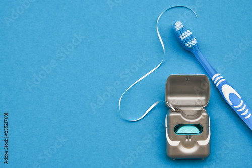 Dental floss and toothbrush on a blue background with copy space