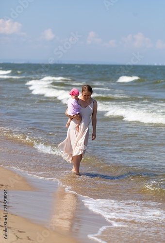 Mother with small baby girl relaxing on sea beach