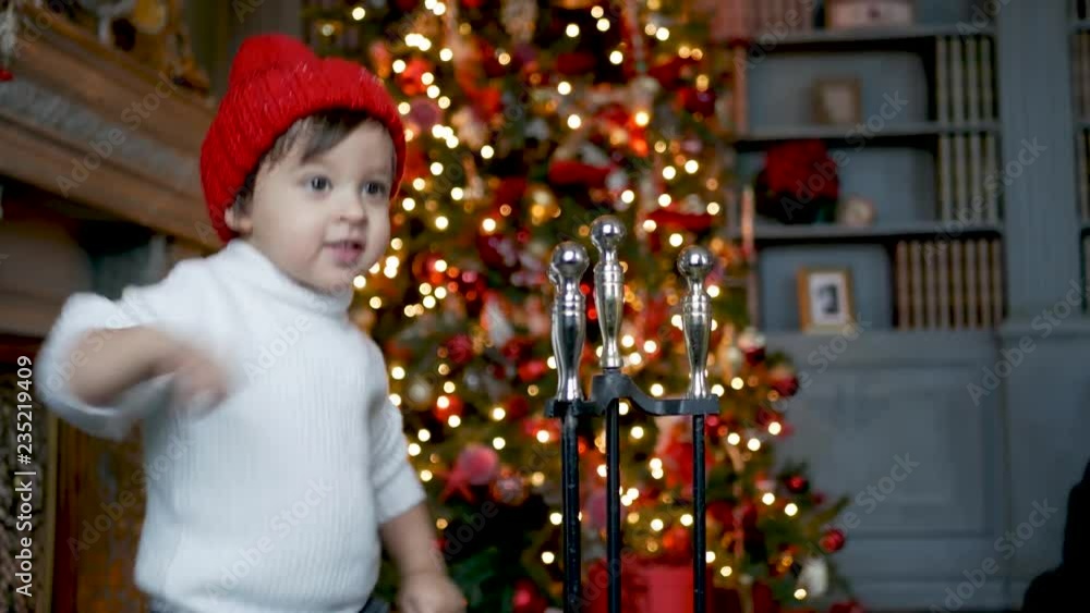 child stands in front of a Christmas tree with toys near the fireplace with accessories child stands in front of a Christmas tree with toys near the fireplace with accessories