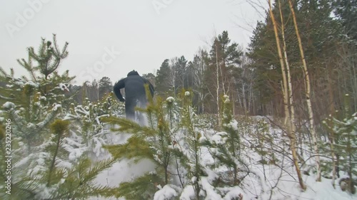 Professional extreme sportsman biker cool riding fat bike in outdoors. Extremal ride through an pine trees. Man does trick on mountain bicycle with big tire in helmet, glasses. Slow motion in 180fps. photo