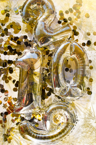conceptual for new years holidays, big ballons forming the 2019 word are laid down a flat board with golden and silver confetti , whistles,top view, natural hard backlight.