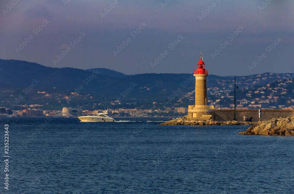 Lighthouse in the port of Saint-Tropez and a boat passing by in the port of Saint-Tropez in the French Riviera in France