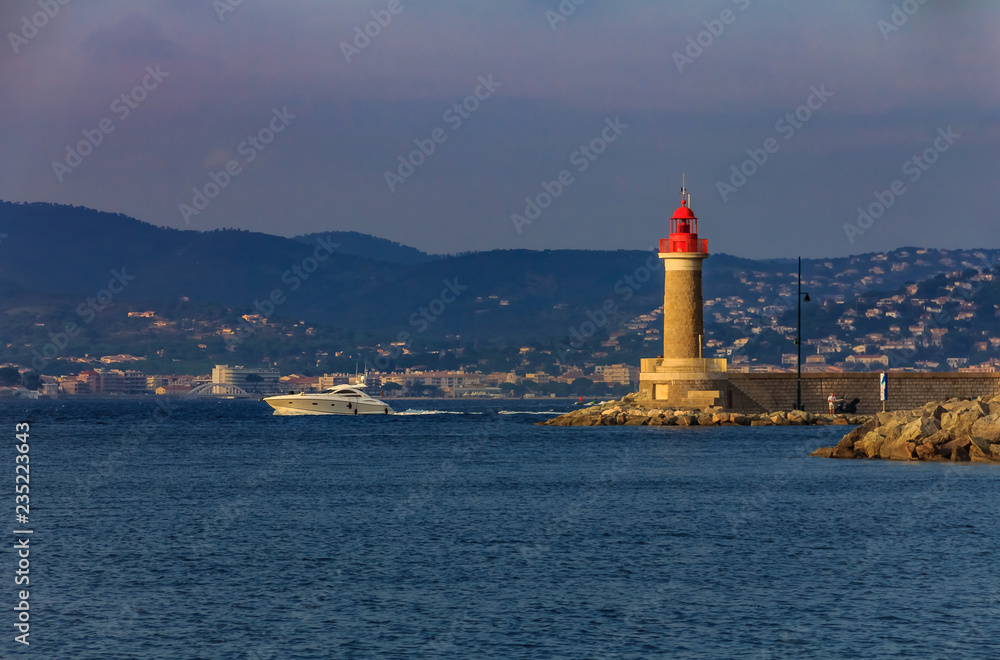 Lighthouse in the port of Saint-Tropez and a boat passing by in the port of Saint-Tropez in the French Riviera in France Lighthouse in the port of Saint-Tropez and a boat passing by in the port of Saint-Tropez in the French Riviera in France
