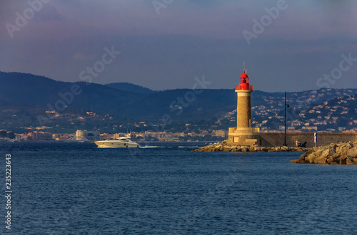 Lighthouse in the port of Saint-Tropez and a boat passing by in the port of Saint-Tropez in the French Riviera in France