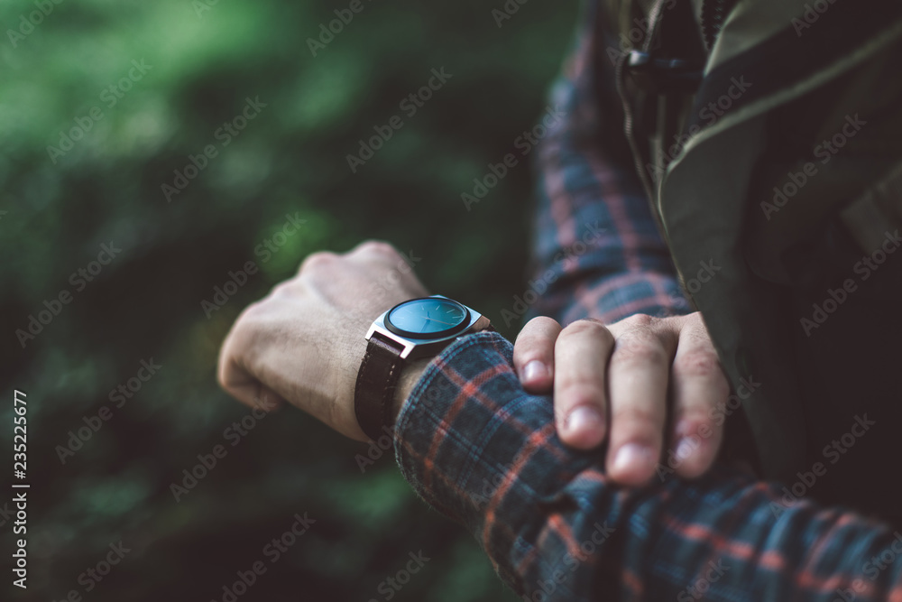 Being in time concept. Close up portrait of male traveler looking at his watch