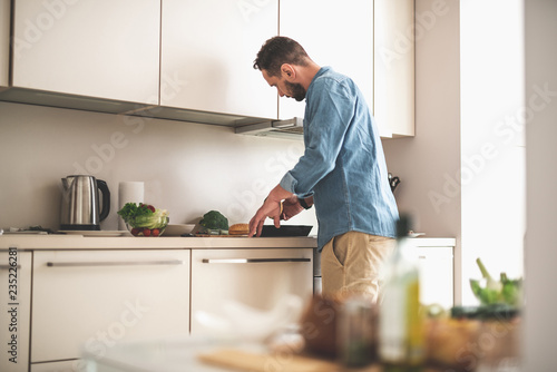Side view portrait of handsome gentleman in denim shirt preparing ingredients for cooking dinner at home