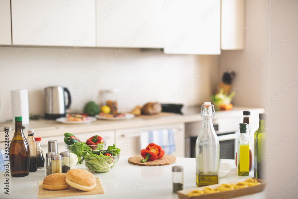 Kitchen desk with cutting board, red bell pepper, olive oil, lettuce, spices and burger buns Kitchen desk with cutting board, red bell pepper, olive oil, lettuce, spices and burger buns